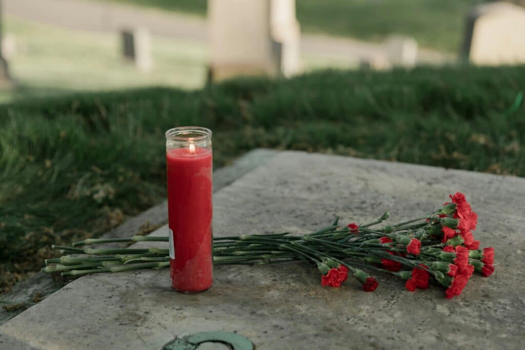 Photo by RDNE Stock project: https://www.pexels.com/photo/red-flowers-and-candle-on-a-tomb-8865073/