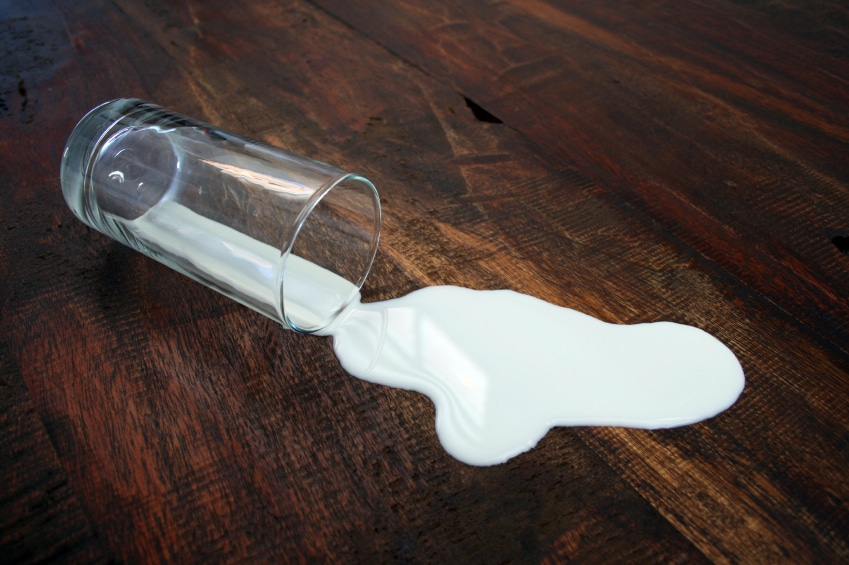 glass-of-spilled-milk-on-wooden-floor