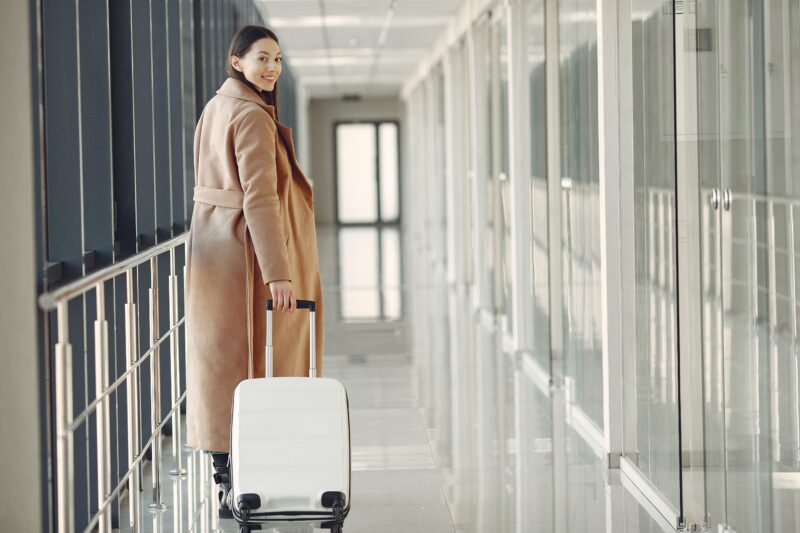 woman-in-longcoat-with-luggage-at-airport