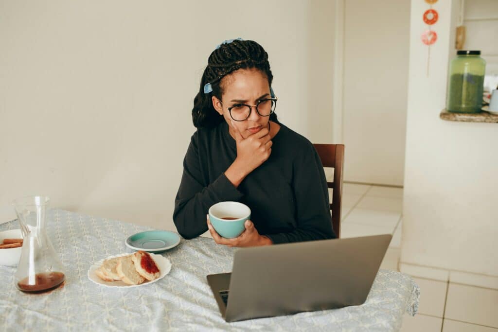woman eating breakfast and solving a problem on her laptop