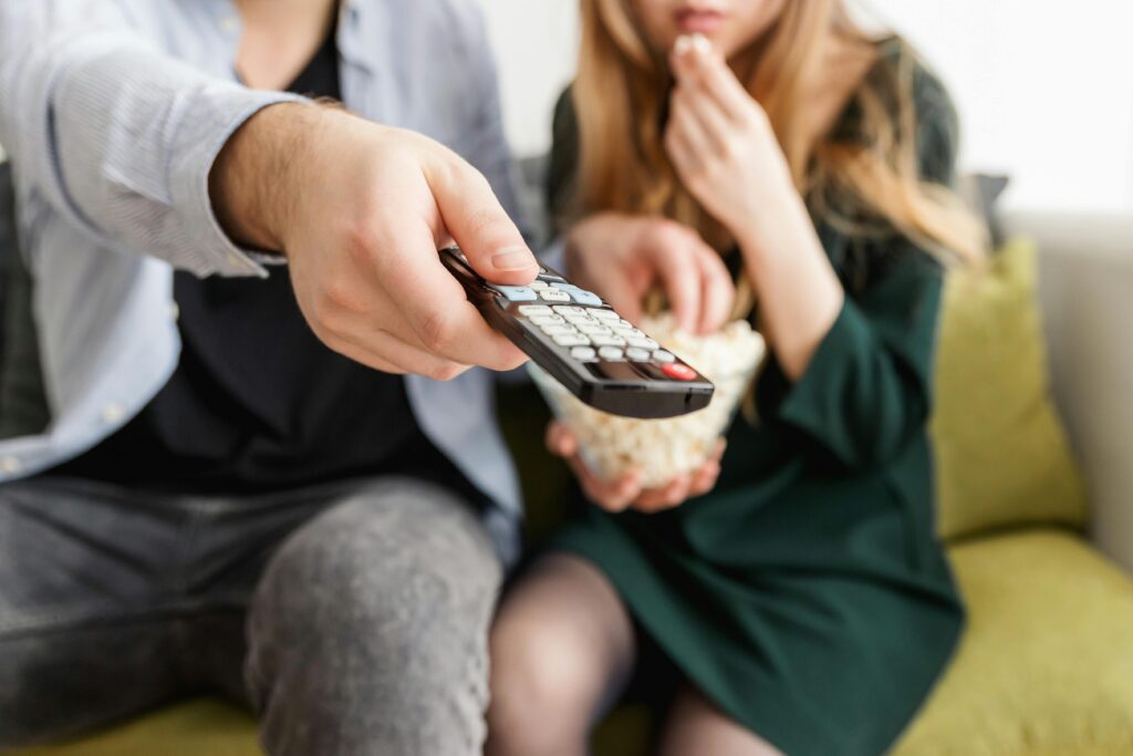 Couple watching TV with remote and popcorn