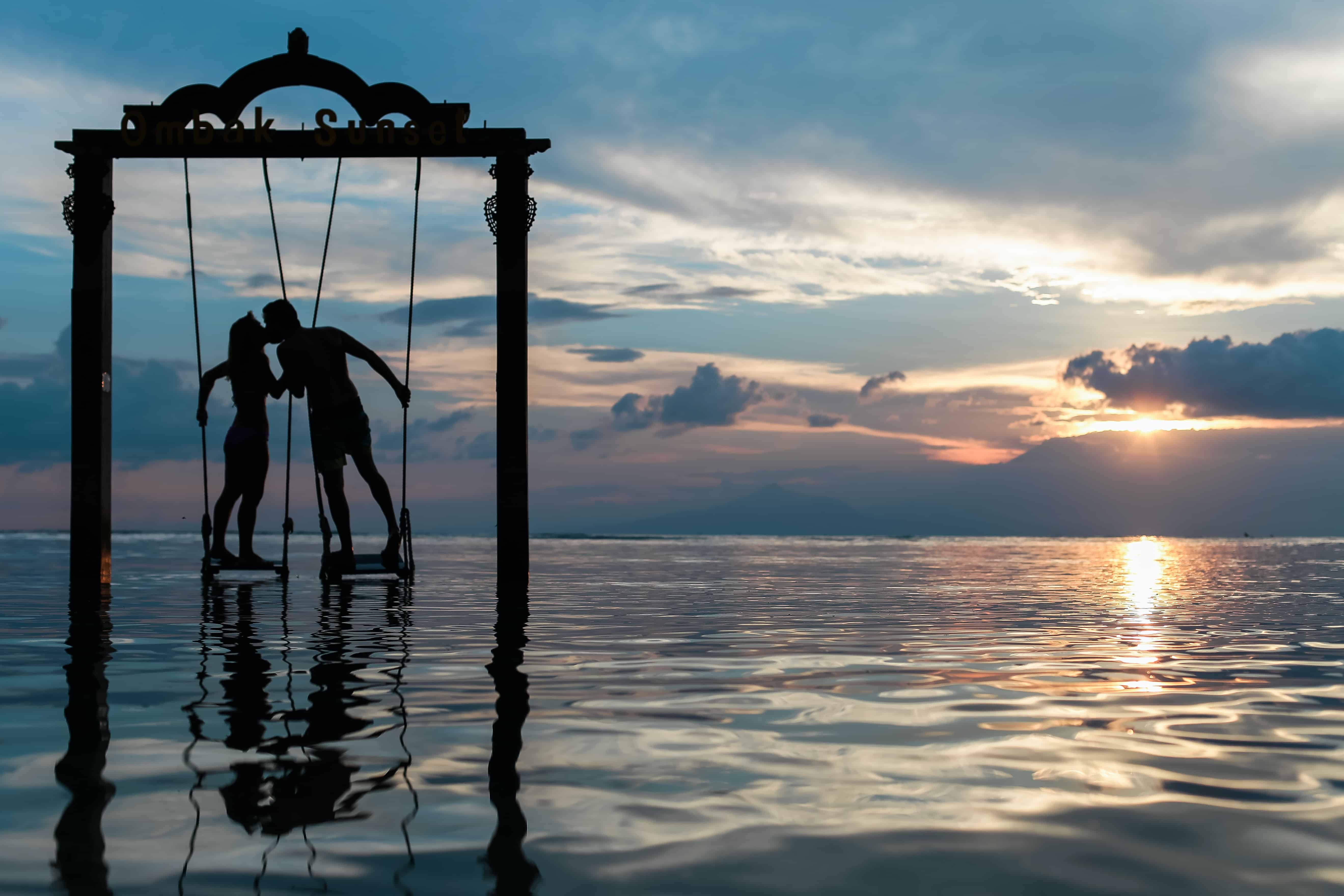 A couple stands on a swing in the ocean