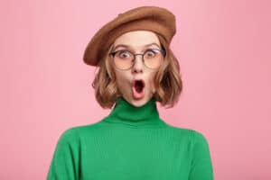 woman wearing beret and glasses with rounded mouth