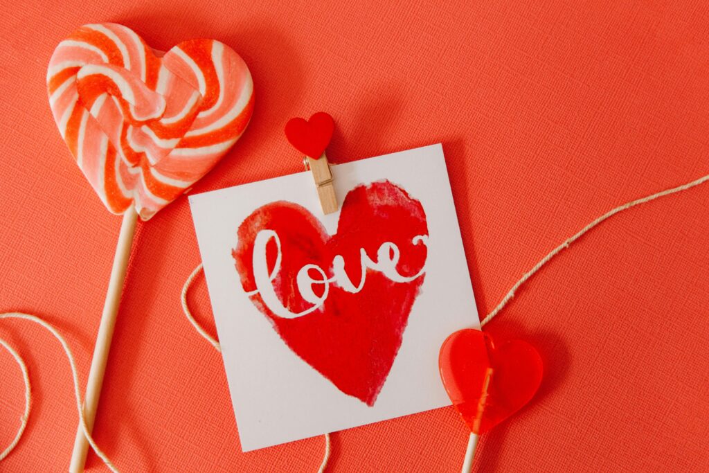 Lollipops on red background with paper that says 'love' on it