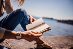 woman reading a book by the water