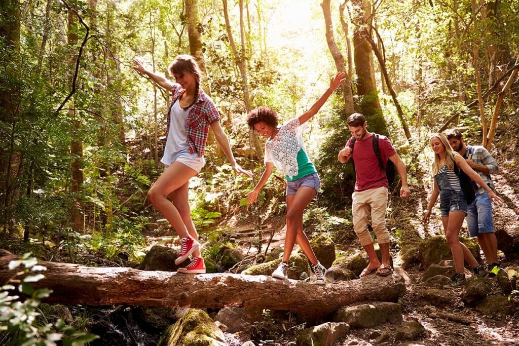 adults walking on a log during a hike