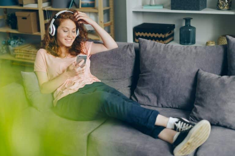 girl smiling on the couch listening to podcasts