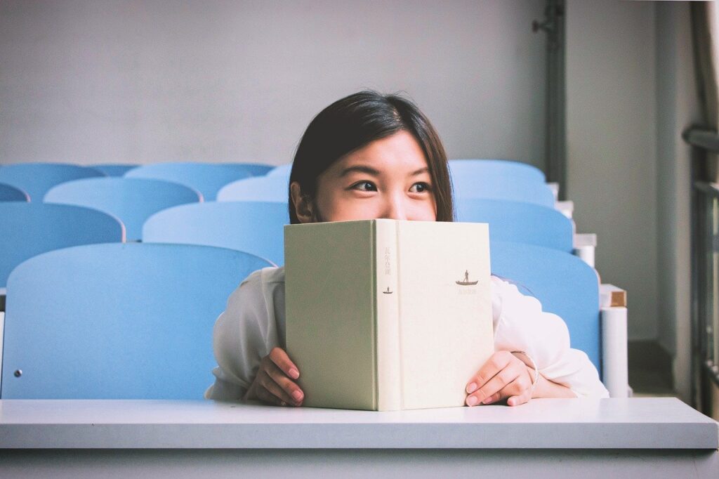 Student in classroom covering half her face with a white book