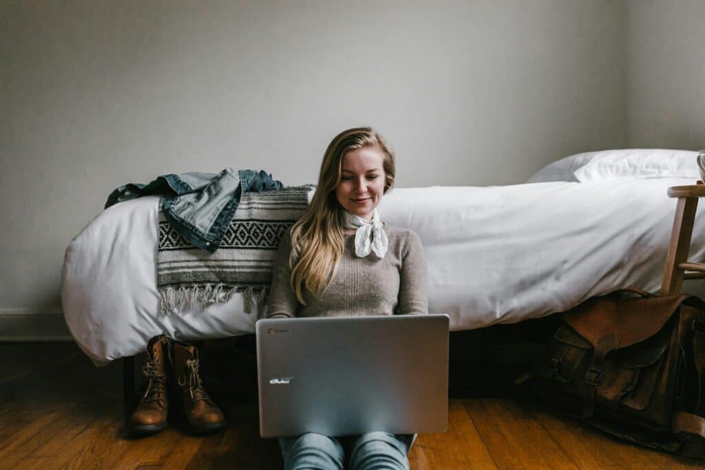 girl sitting on bedroom floor using laptop