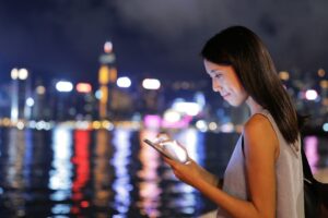 Woman checking her phone at the riverfront at night