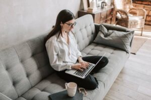 woman sitting on the couch typing on her laptop