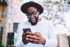 happy man in a hat texting on his phone