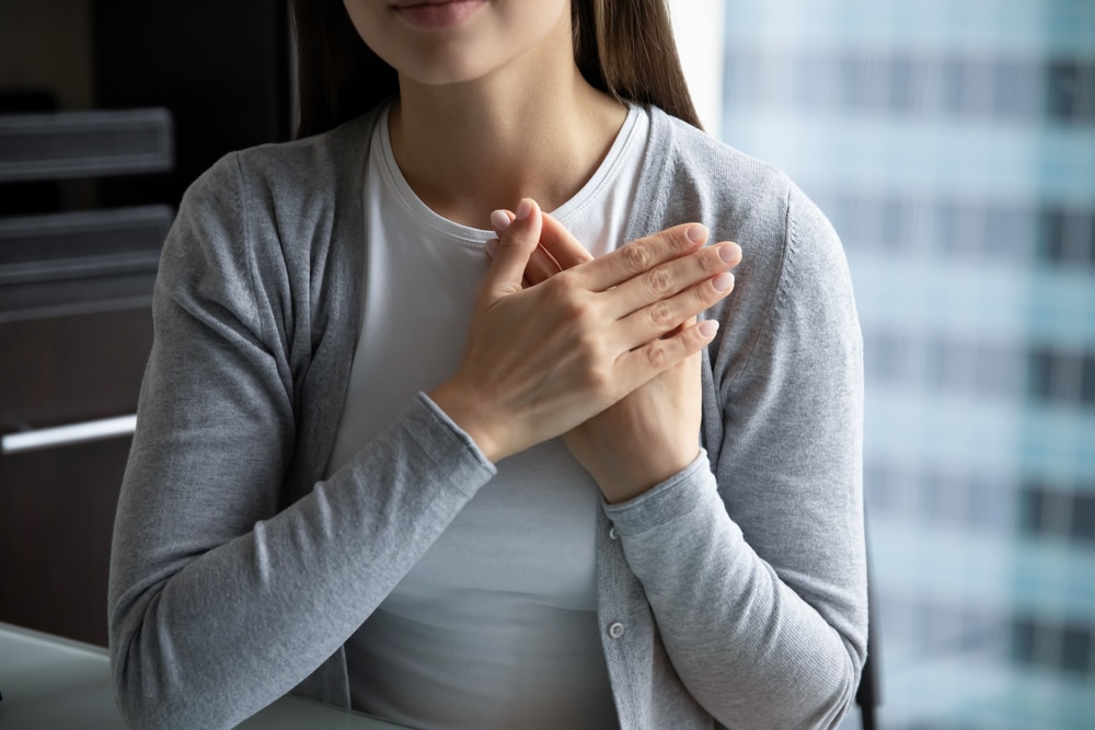 woman holding both hands in her chest