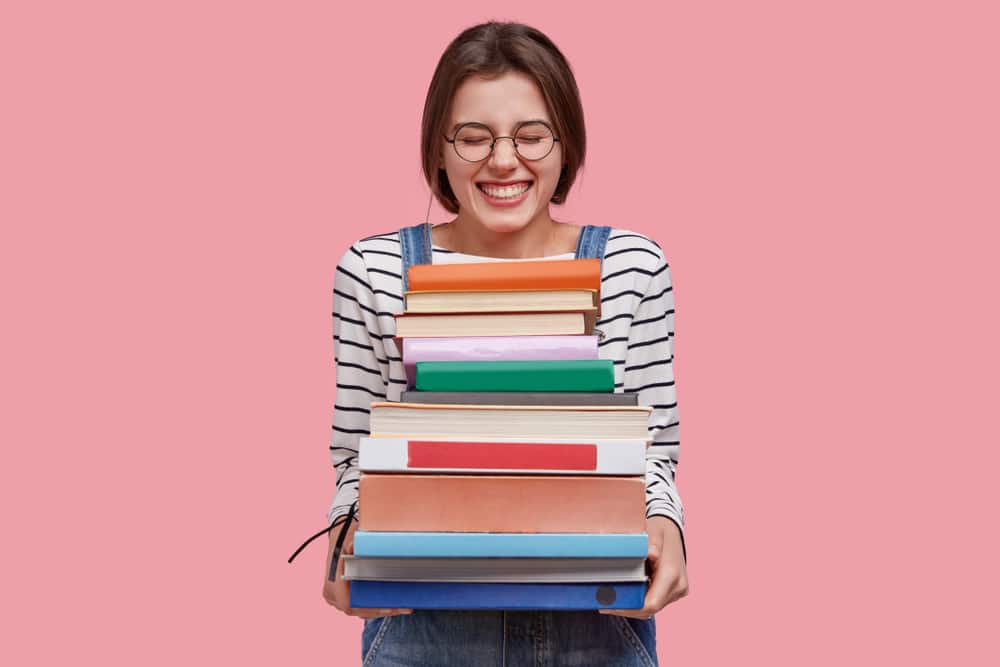 smiling woman holding a stack of books