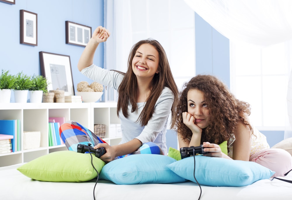 two teenage girls playing video games with each other