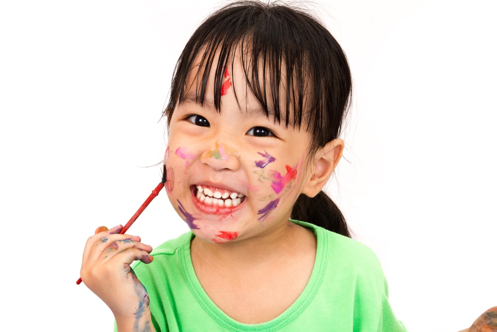 young toddler girl smiling and painting on her face