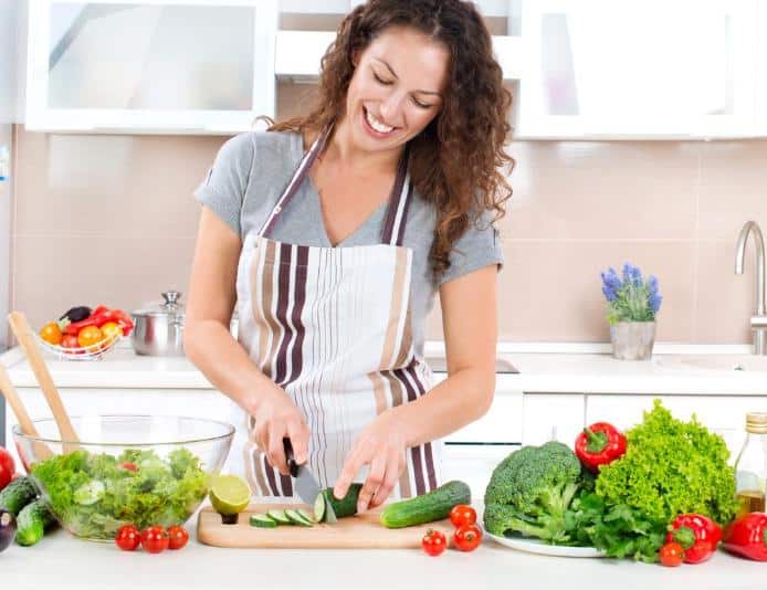 brunette woman chopping vegetables and making salad