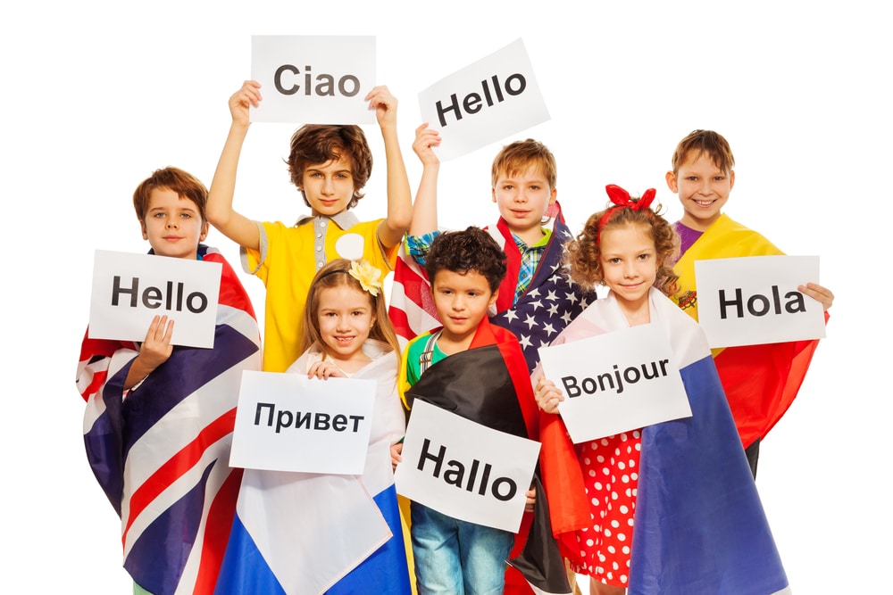 young kids holding signs with "hello" in different languages and wearing country flags