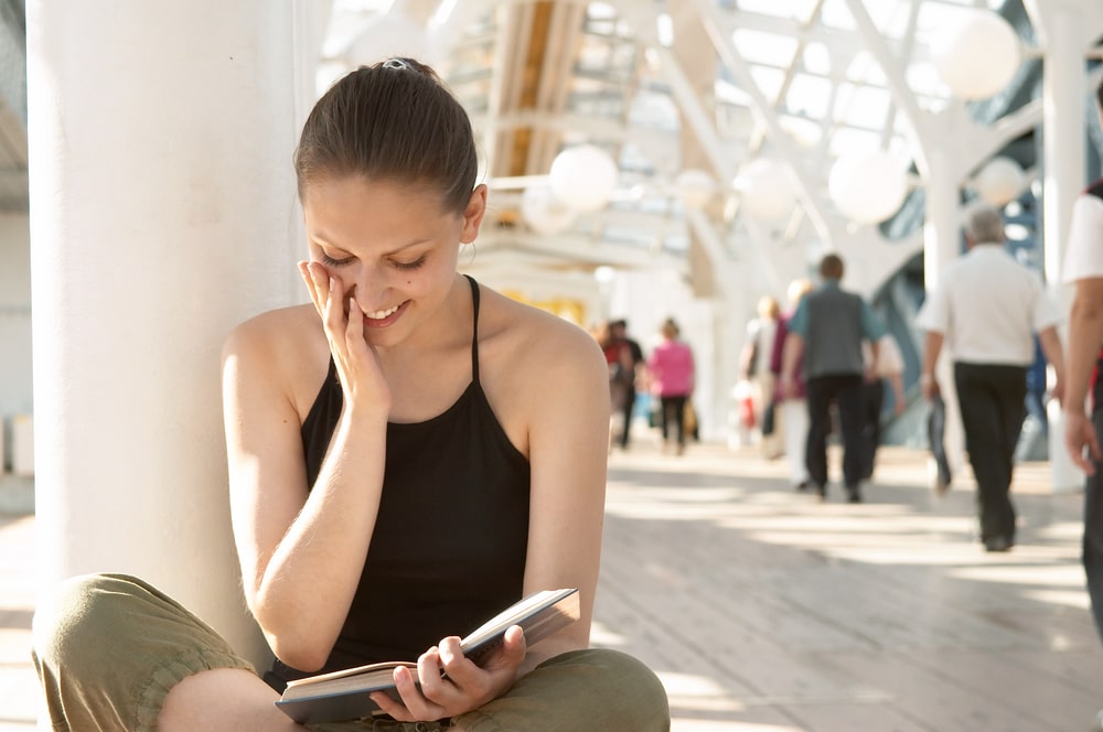 young woman sitting by herself reading a book