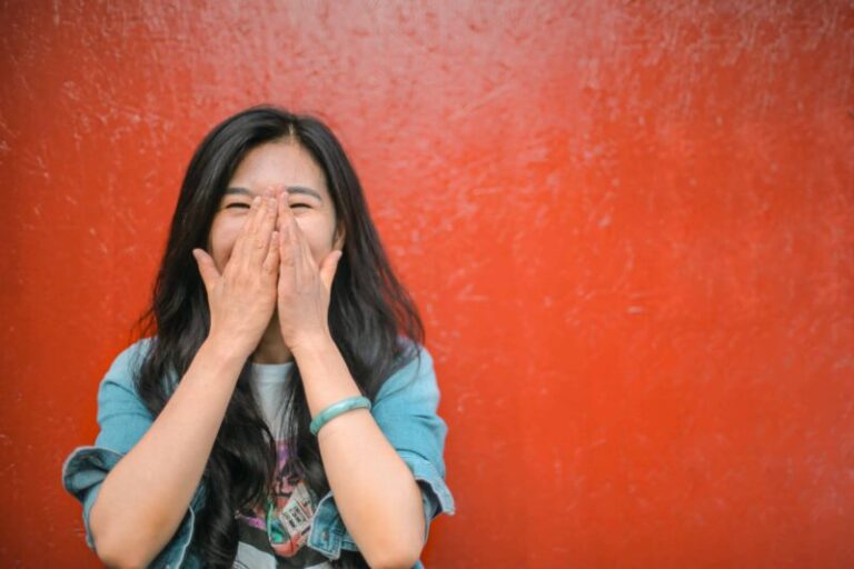 asian woman covering her mouth while laughing