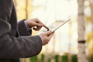 person holding and using tablet in the woods