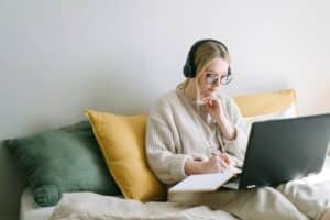 woman-on-laptop-with-headphones-and-notebook