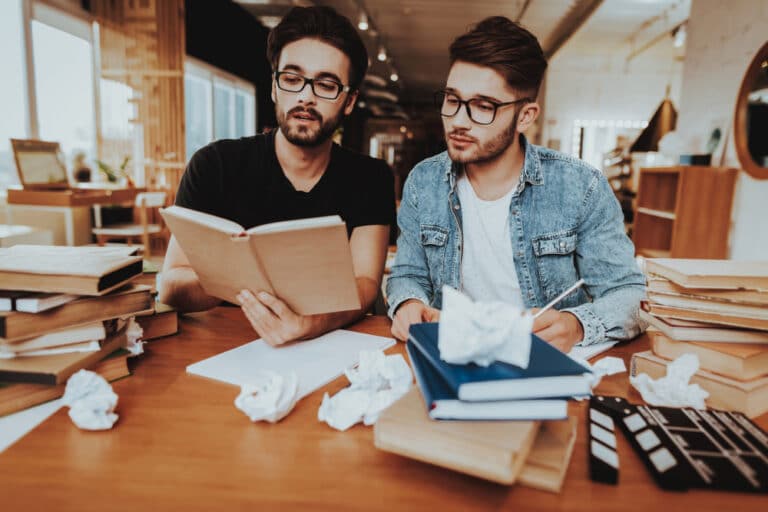 two men reading books indoors