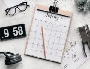 calendar, clock, glasses, water bottle and other items on a desk