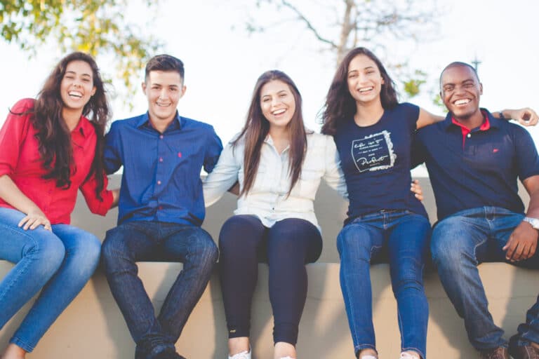 Group of people sitting on a bench smiling