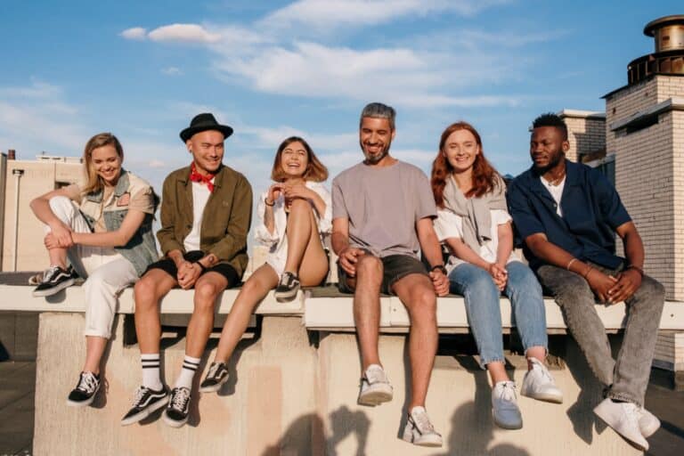 group-of-friends-sitting-on-a-curb-together-and-smiling