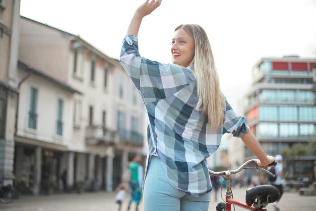 Back of woman waving while holding bike