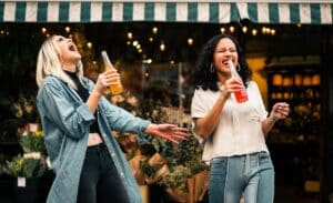 Two women laughing with sodas in their hands