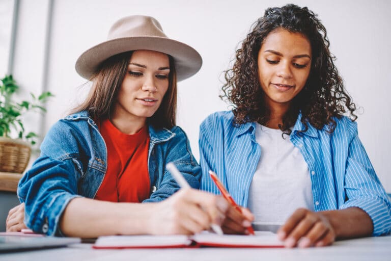 two women writing in a notebook