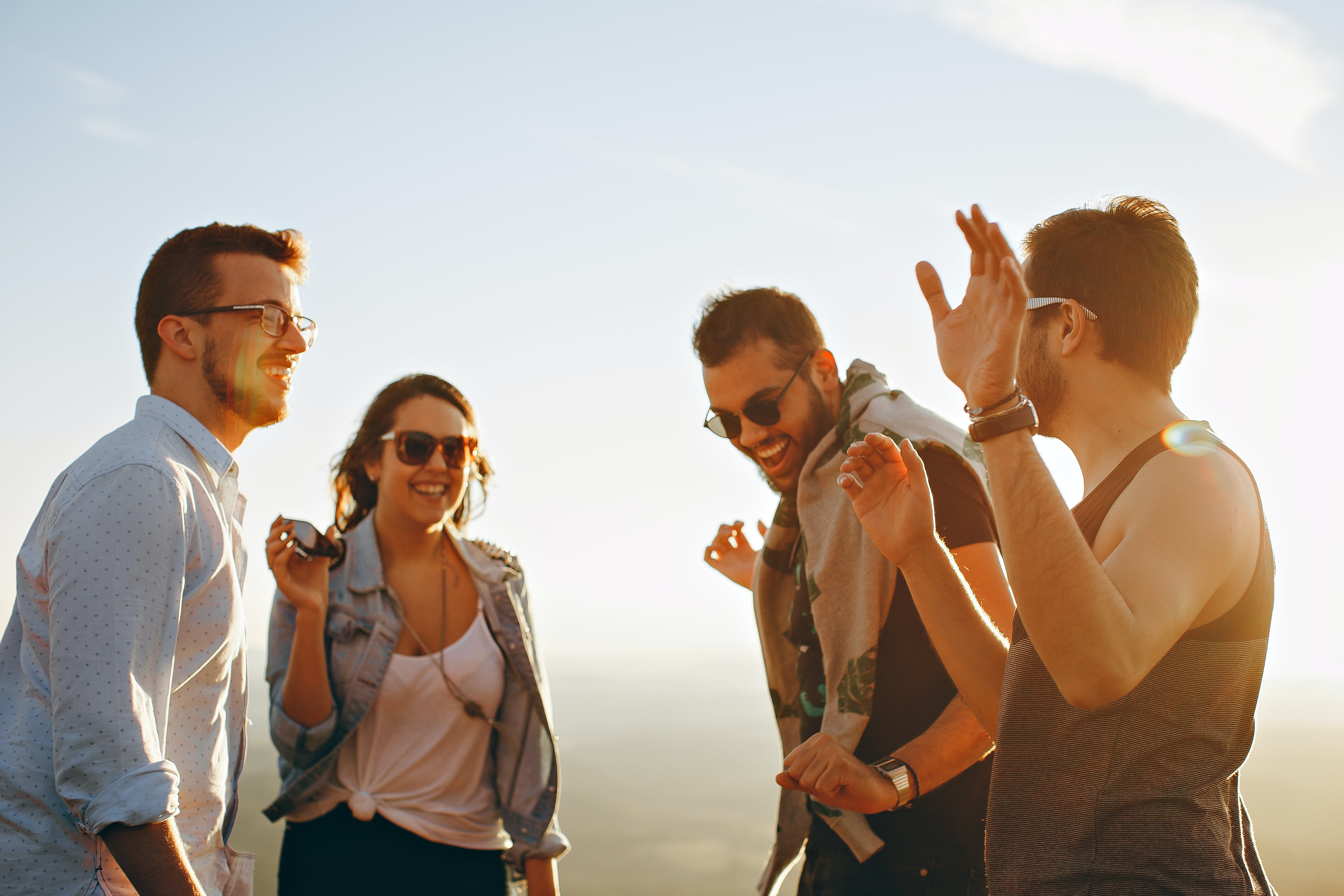 A group of friends talks and laughs on the beach at sunset