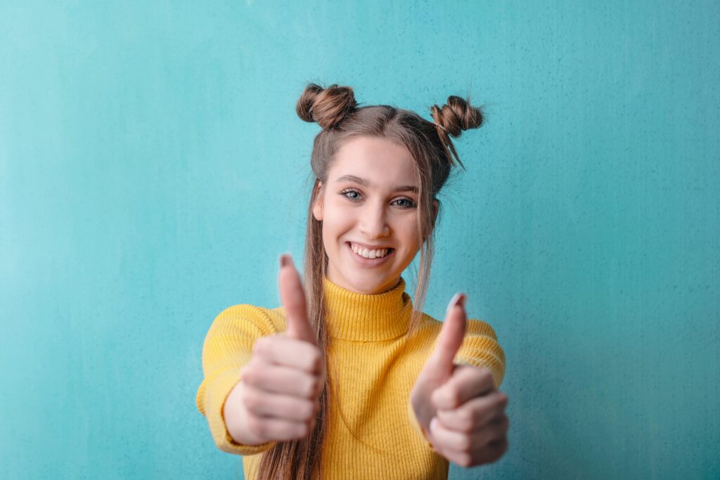 Woman in yellow top giving two thumbs up