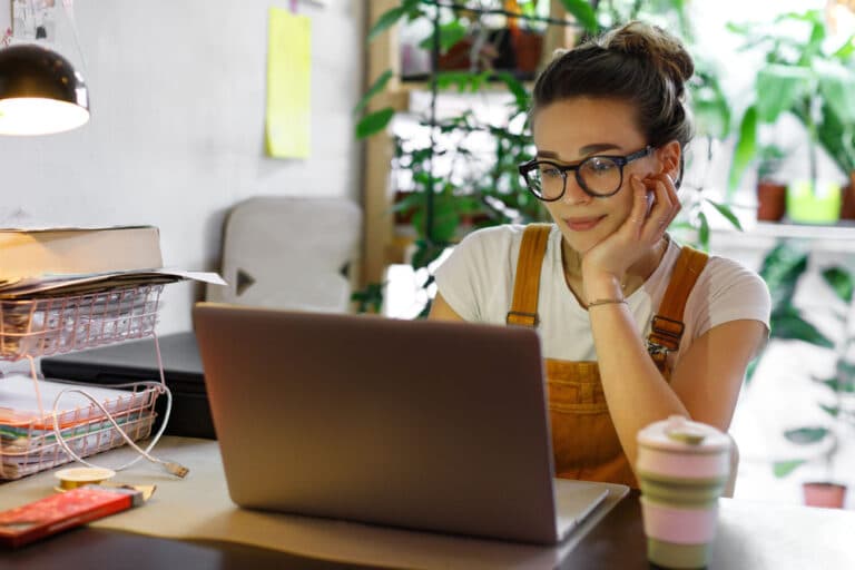 brown-haired-young-woman-smiling-while-using-a-laptop