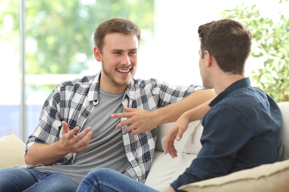 two men sitting on a sofa chatting