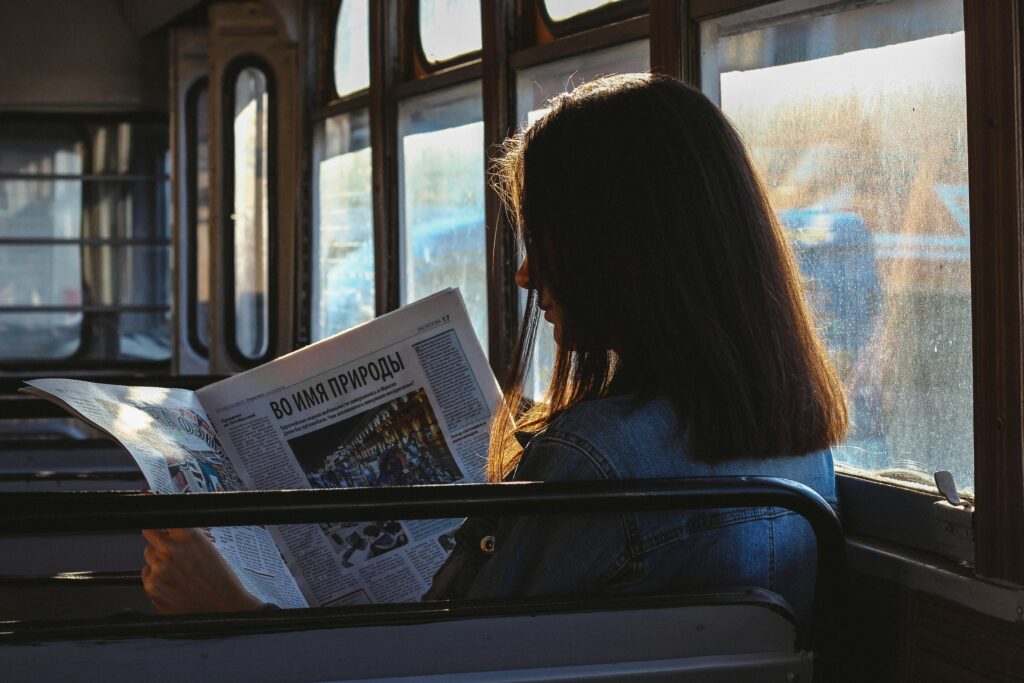 woman-reading-newspaper-on-bus