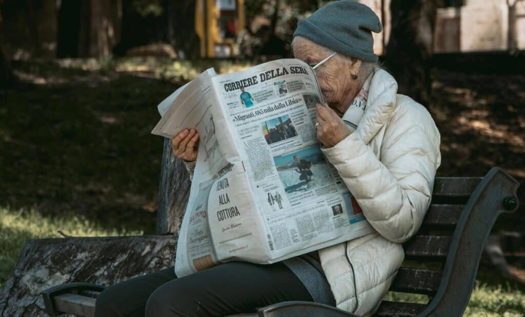 elderly-woman-reading-Italian-newspaper-on-bench