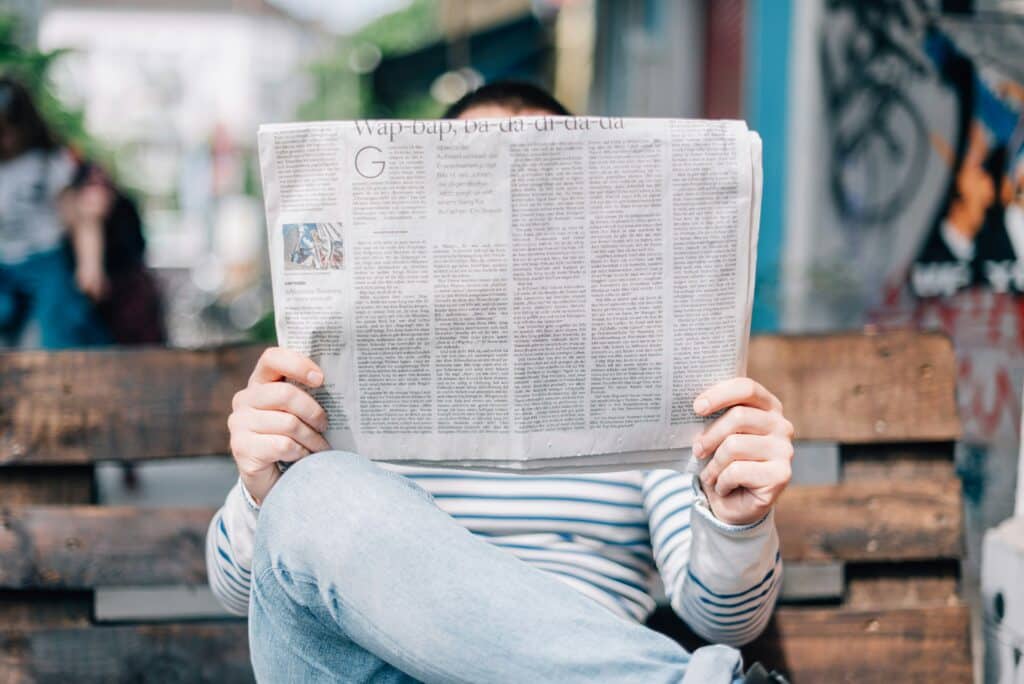 man-reading-newspaper-on-bench