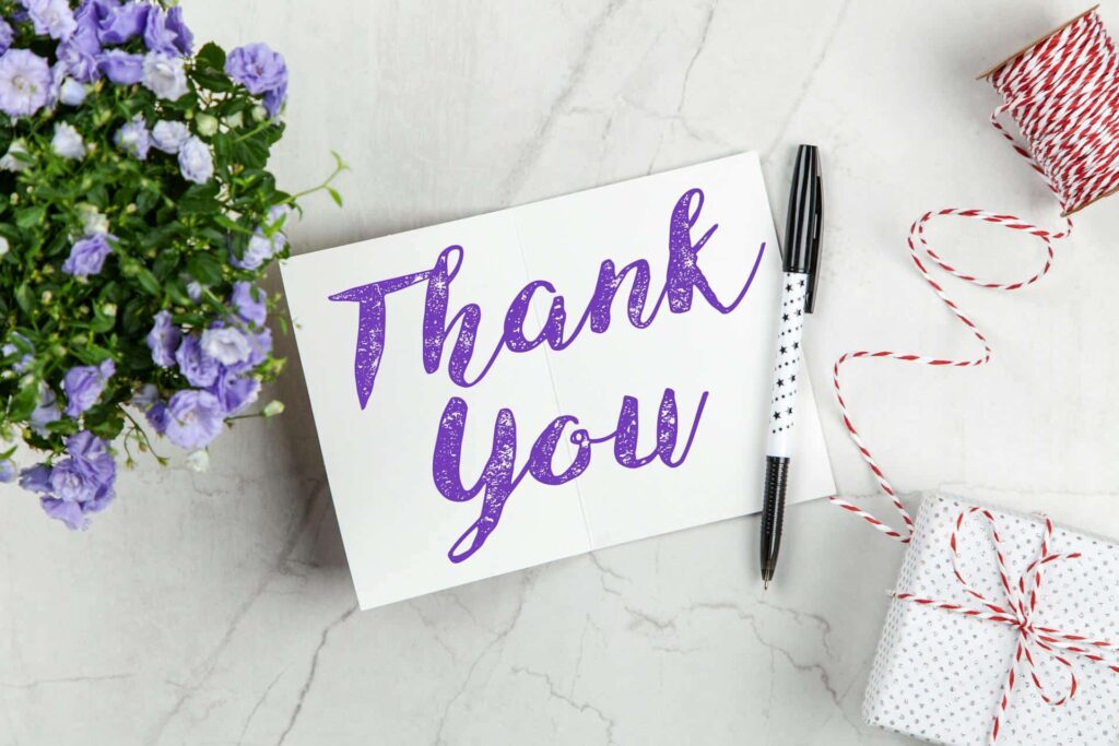 thank-you-card-flanked-by-purple-flowers-red-string-and-white-gift-box