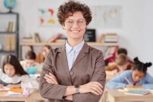 smiling-woman-in-formal-wear-with-arms-crossed-standing-with-her-back-to-students