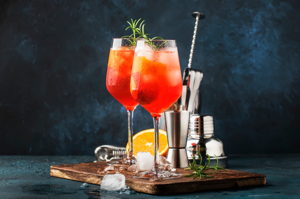 cocktail with orange, equipment, and ice in background