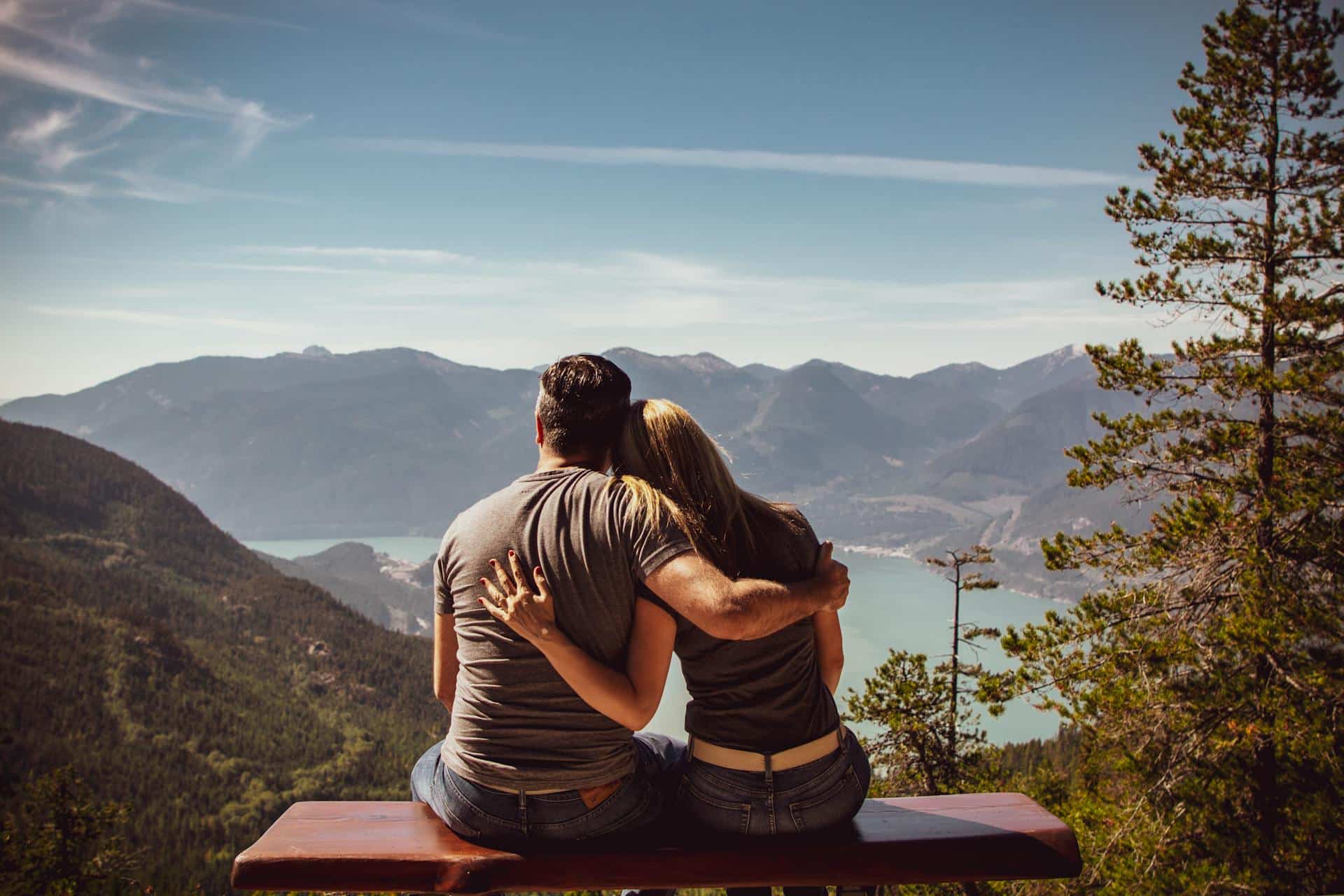 back-shot-of-man-and-woman-sitting-on-wooden-beach-with-arms-around-each-other