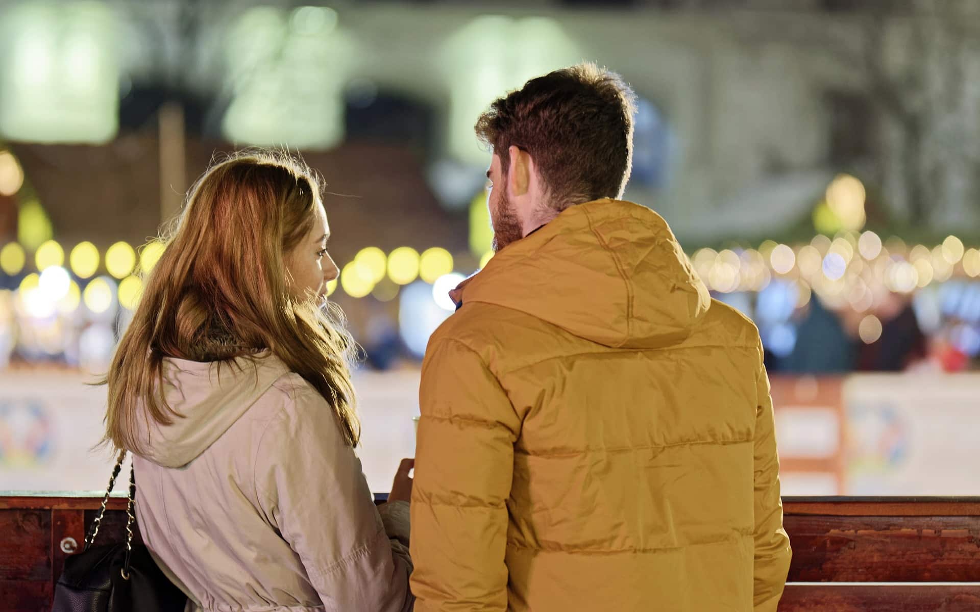 couple talking at night with lights in background