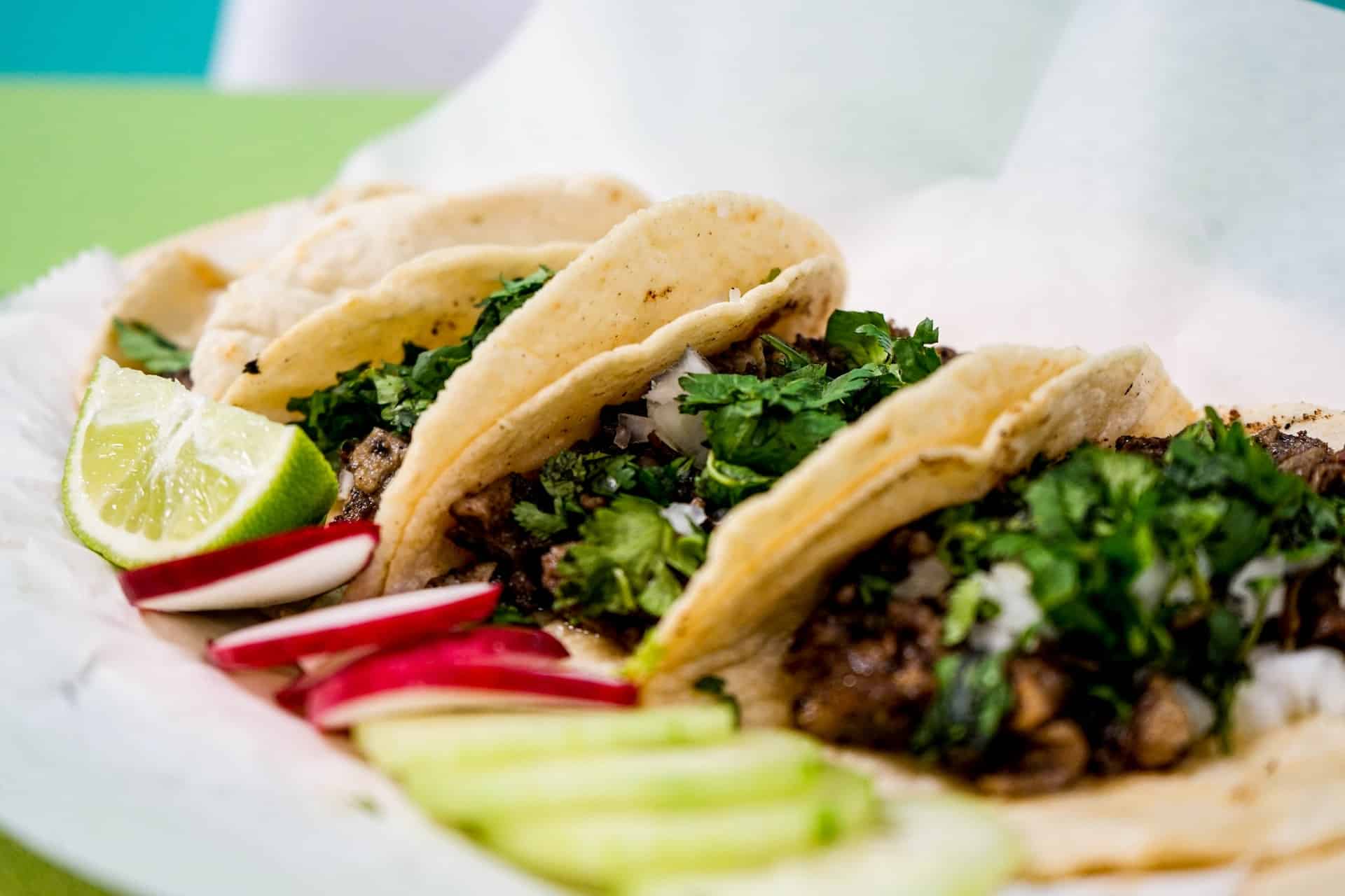 Tacos on a plate with lime and radish