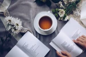 two open books of poems with a cup of tea and flowers on the table