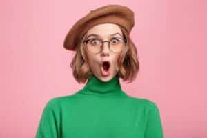 woman wearing a beret and glasses with a rounded mouth