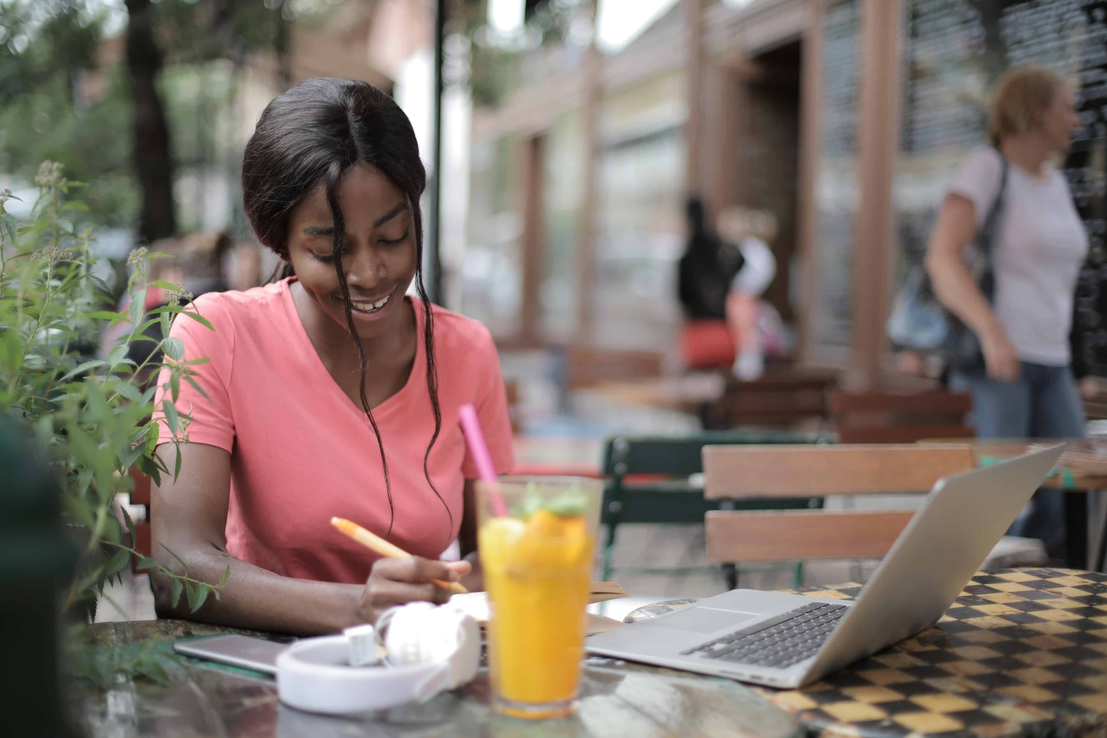 A woman writing at a cafe with her laptop in front of her