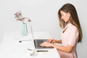 woman sitting at her desk typing on her laptop